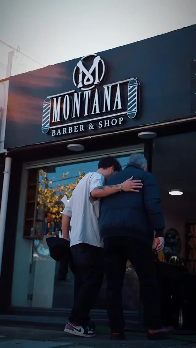 La entrada de la barbería al atardecer, con el letrero de Montana encendido sobre la vitrina.